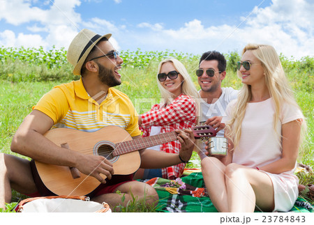 Young people listening guy playing guitar group 23784843