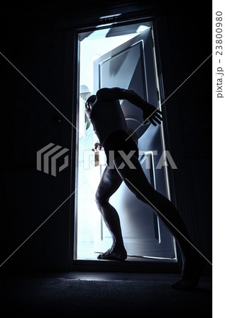 Man enters opening door from black room Man enters opening door from black room 23800980