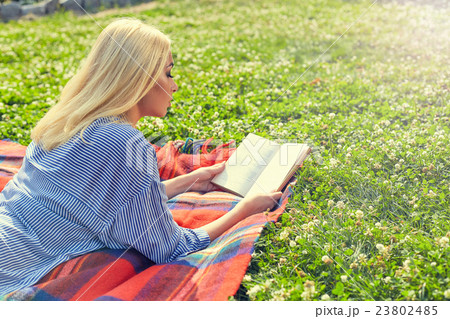 Profile of blonde girl read book on green grass Profile of blonde girl read book on green grass 23802485