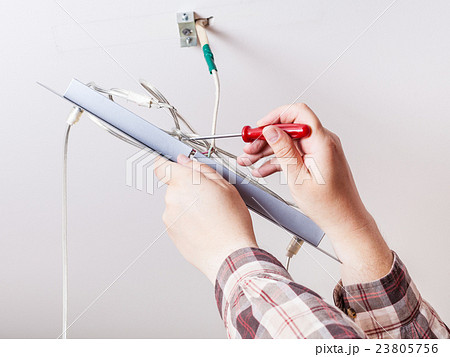 Electrician repairs wiring in ceiling lamp Electrician repairs wiring in ceiling lamp 23805756
