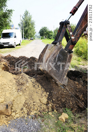 Excavator bucket digging a trench in the ground 23811782