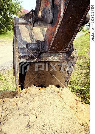 Excavator bucket digging a trench in the  ground 23811784