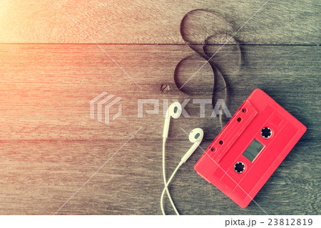 Red cassette tape with earphone over wooden table Red cassette tape with earphone over wooden table 23812819