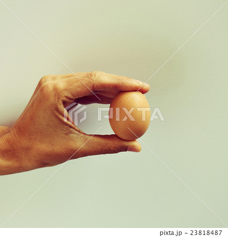 young man with a brown egg in his hand 23818487