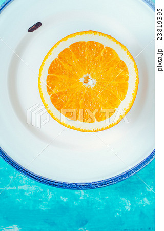 Half of orange on plate on the cyan background  23819395