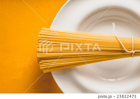 Raw spaghetti  on the  plate on the background  23822473