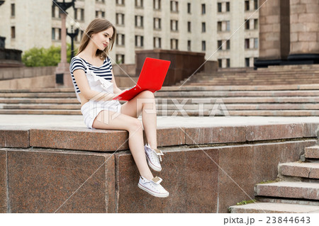 Young woman with laptop sitting on stairs near the 23844643