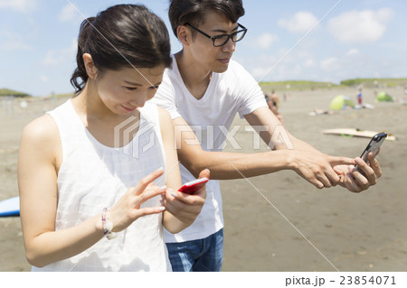 ポケモンgo イメージ カップル 海水浴場 モンスターを探す 発見した模様 湘南 江ノ島 風の写真素材