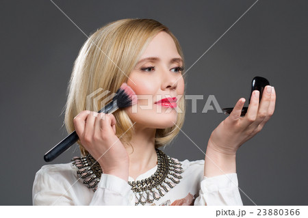 Beautiful middle aged woman applying blush 23880366