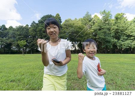 ポケモンgo イメージ 兄弟で夢中 公園 夏 ゲットしてガッツポーズ カメラ目線の写真素材