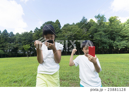 ポケモンgo イメージ 兄弟で夢中 公園 夏 ゲットしてガッツポーズ 目線なしの写真素材