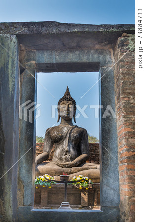 View of Sitting Buddha statue through stone door 23884711