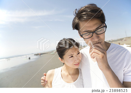 カップル 海 肩を抱く 男性悩む 湘南の写真素材