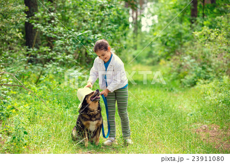 Happy little girl playing with dog in the forest Happy little girl playing with dog in the forest 23911080