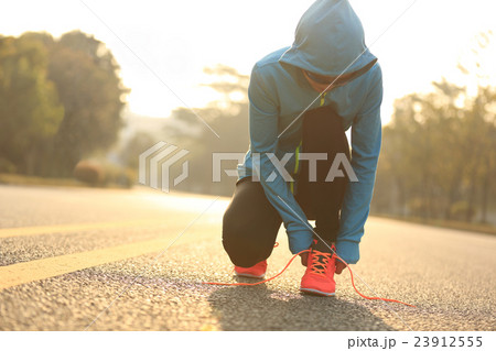 young fitness woman runner tying shoelace on road 23912555