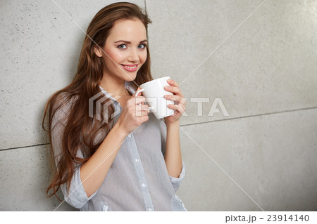 woman sitting on the couch with a cup 23914140