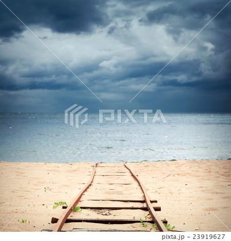 Old rusted railway goes over sandy beach 23919627