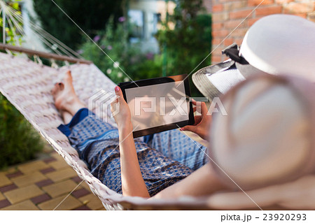 Woman using tablet computer while relaxing in a Woman using tablet computer while relaxing in a 23920293
