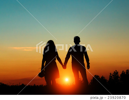 Silhouetted loving couple at sunset 23920870