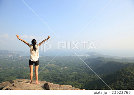 young freedom woman open arms on mountain peak 23922769