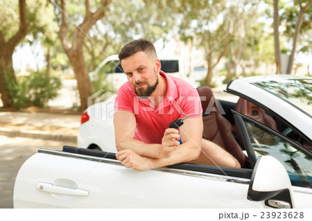 Bearded man standing near convertible with keys in hand Bearded man standing near convertible with keys in hand 23923628