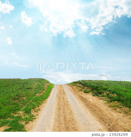 rural road in green grass to sun in blue sky 23926209