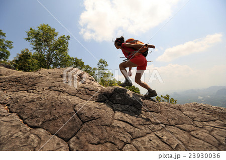 youngwoman hiker climbing on mountain peak cliff youngwoman hiker climbing on mountain peak cliff 23930036