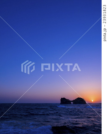 マジックアワーに和歌山白浜、円月島に沈む夕日と荒波 23931823
