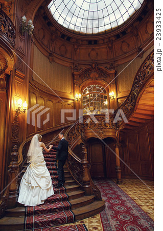 Groom and bride go upstairs in an old wooden hall Groom and bride go upstairs in an old wooden hall 23933425