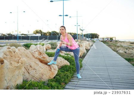 Woman resting after jogging on a wooden path at the sea 23937631
