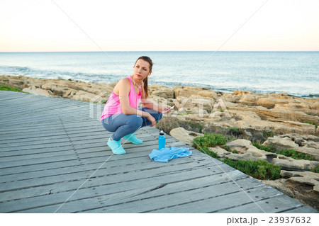 Woman resting after jogging on a wooden path at the sea 23937632