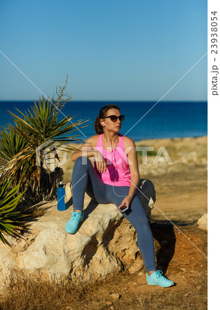 Girl resting after jogging on the rock at the sea 23938054