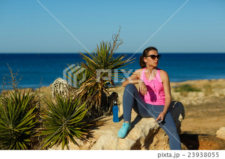 Girl resting after jogging on the rock at the sea Girl resting after jogging on the rock at the sea 23938055