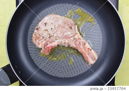 Chef cooking porkchop in frying pan 23957704