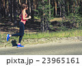 Young fitness woman running on forest trail 23965161
