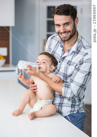 Father feeding milk to son at table Father feeding milk to son at table 23969997
