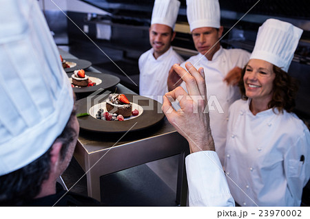 Head chef showing ok hand sign after inspecting dessert plates Head chef showing ok hand sign after inspecting dessert plates 23970002