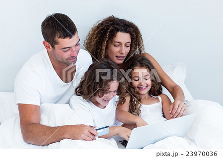 Family with credit card shopping online on bed Family with credit card shopping online on bed 23970036
