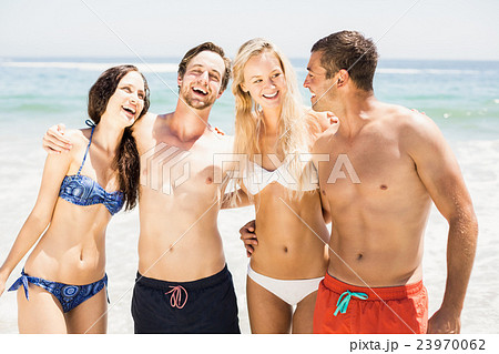 Happy friends standing and talking together on the beach Happy friends standing and talking together on the beach 23970062