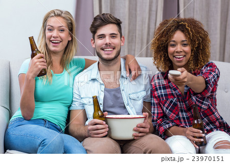 Happy friends watching soccer match while sitting on sofa Happy friends watching soccer match while sitting on sofa 23970151