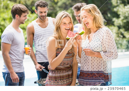 Young women smiling and having a slice of water melon Young women smiling and having a slice of water melon 23970465