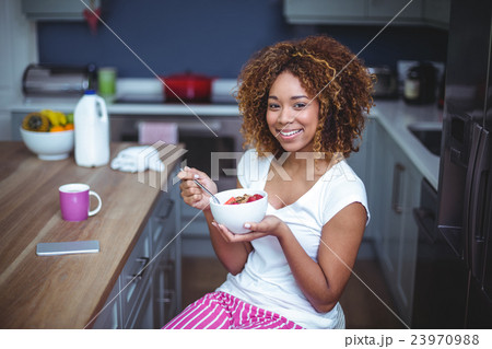 Happy young woman having breakfast in kitchen Happy young woman having breakfast in kitchen 23970988