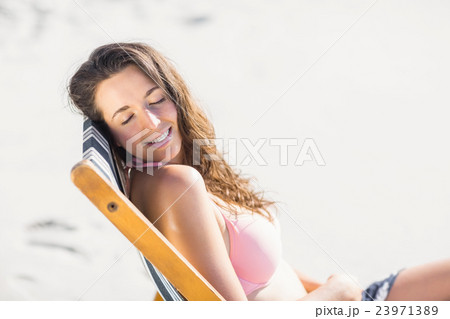 Happy woman sitting on an armchair with eyes closed 23971389