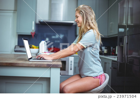 Happy beautiful woman using laptop at table in kitchen 23971504