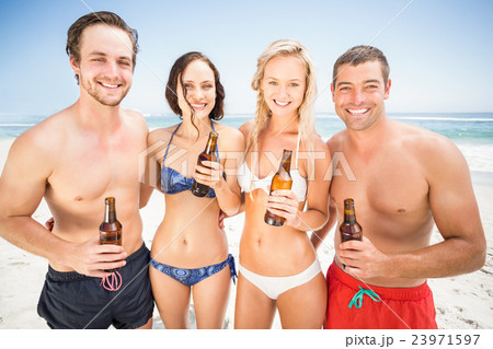 Portrait of happy friends standing on the beach with beer bottle Portrait of happy friends standing on the beach with beer bottle 23971597