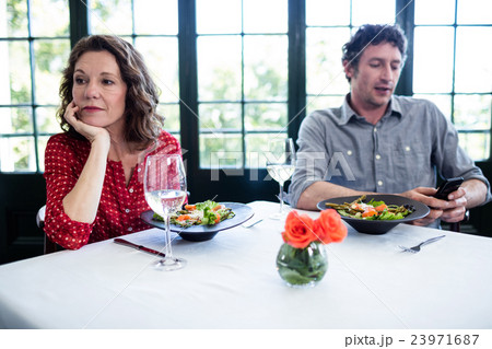 Woman feeling bored while man using his phone Woman feeling bored while man using his phone 23971687