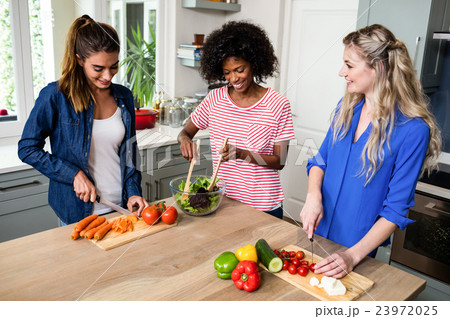 Cheerful young female friends preparing food 23972025