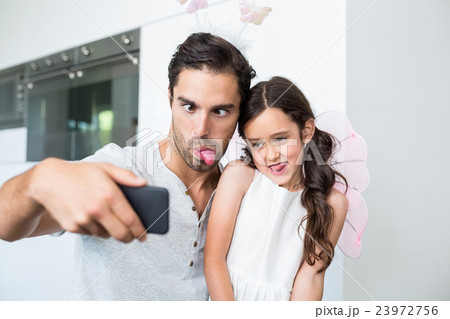 Father and daughter making faces while taking self portrait Father and daughter making faces while taking self portrait 23972756