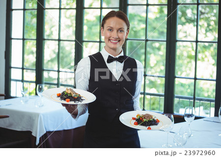 Smiling waitress holding plates 23972960