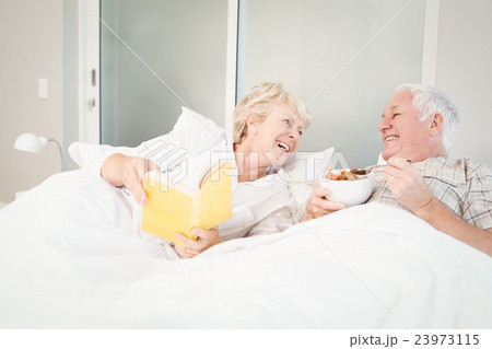 Senior couple reading book in bed 23973115